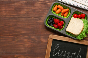 Lunch box with tasty food and chalkboard on wooden background