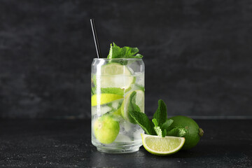 Glass of fresh Mojito cocktail with limes and mint on black background