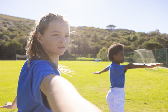 Fototapeta Practicing stretching exercises, diverse girls in school enjoying outdoor activity on sports field