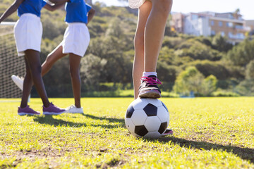 Fototapeta premium Playing soccer on school field, diverse girls in sports uniforms enjoying game