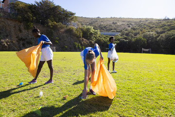 Obraz premium In school, diverse girls picking up trash on field, participating in cleanup activity