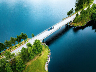 Aerial view of bridge asphalt road with car driving over blue water lake in Finland