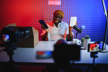 Young african american man recording or streaming podcast using microphone at his small broadcast...