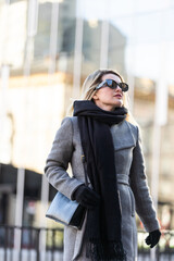 Fototapeta premium The girl in a coat walks around the city on a sunny day