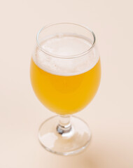 A frothy glass of fresh beer against a bright yellow background