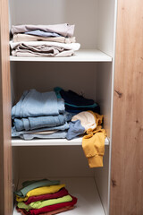 neatly folded clothes lying on the shelves of the wardrobe