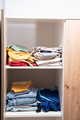 neatly folded clothes lying on the shelves of the wardrobe