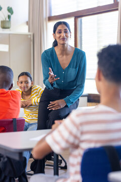 In school, Indian female teacher engaging with students, fostering interactive learning environment