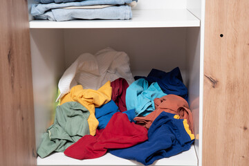 neatly folded clothes lying on the shelves of the wardrobe