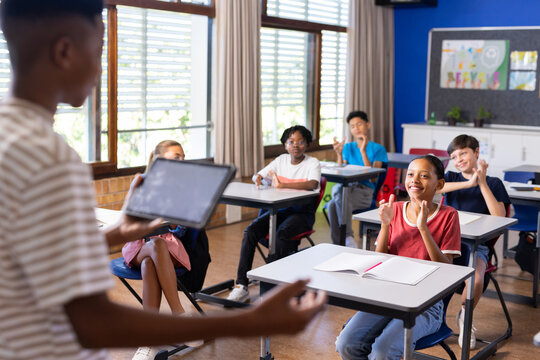 Presenting project on tablet, student engaging classmates in school activity - Powered by Adobe