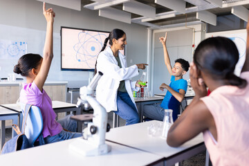 Fototapeta premium Engaging students in science classroom, Indian female teacher using microscope and beakers
