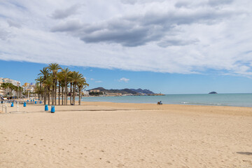 Photo of the beautiful town of Villajoyosa in Spain showing the lovely sandy beaches on a hot sunny day with palm trees on the beach