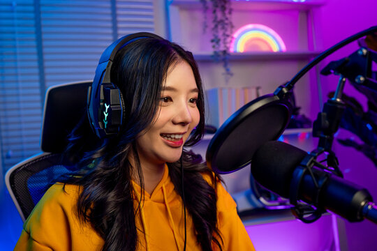 Asian audio DJ woman talking on microphone to broadcasting in neon room. 