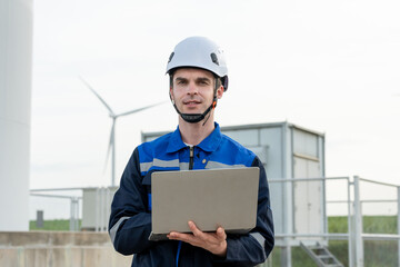 Caucasian male technician working outdoors in the wind turbines field. 