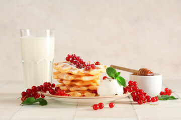 Delicious Belgian waffles with redcurrant, honey, ice cream and glass of milk on table against...