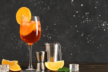 Glass of Aperol spritz cocktail with ice cubes on wooden table