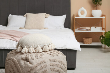 Stylish pillow on pouf in bedroom, closeup