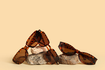 Stones with stylish sunglasses on beige background