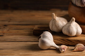 Board with fresh garlic on wooden background