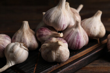 Board with fresh garlic on wooden background