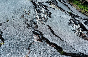 Cracked asphalt surface showing significant damage from seismic activity, highlighting aftereffects...