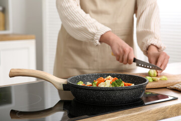 Young woman cutting tasty Brussels sprouts in kitchen