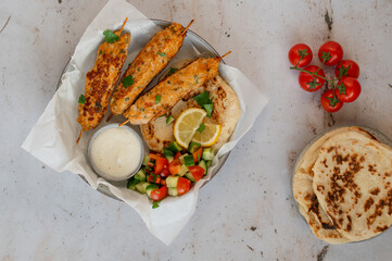 Chicken Kofta Kebab on wooden skewers with pita, garlic sauce Toum, parsley, lemon, cucumber and tomato. Shish kafta tavuk. Traditional Middle East food. Lebanese, Turkish cuisine. Food photography.