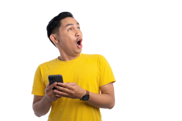 Surprised young Asian man holding smartphone and looking aside at copy space isolated on transparent background