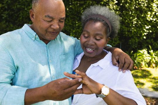 Senior couple enjoying moment together outdoors, exchanging rings with joy