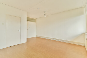 A simple and clean interior room showcasing light-colored walls and wooden flooring, providing a...