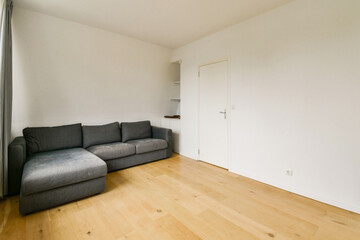 A clean and minimalist living room featuring a gray sofa and neutral-colored walls, showcasing a simple and modern aesthetic.