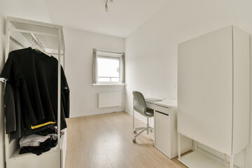 A bright and airy room featuring a simple desk, storage unit, and minimal decor. The clean lines create a serene and uncluttered workspace atmosphere.