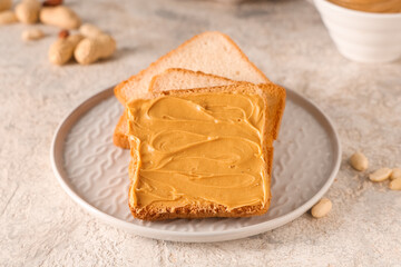 Toasts with tasty peanut butter and nuts on light grunge background