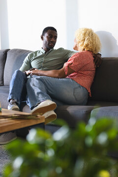 Couple relaxing on sofa, enjoying conversation and quality time at home, copy space