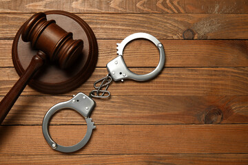 Handcuffs with judge's gavel on wooden background