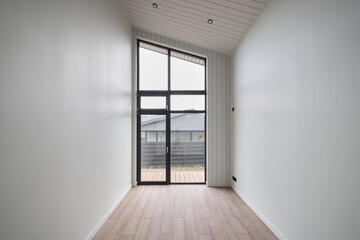 This is a Modern Minimalist Room that features a Large Window and a Beautiful Wooden Floor