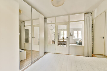 A bright and airy bedroom featuring a minimalist design with mirrored wardrobes, light wood flooring, and soft curtains, creating a serene atmosphere.