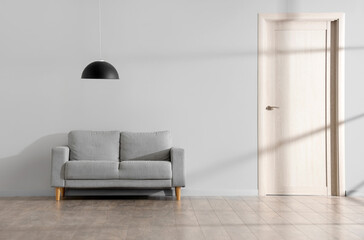 Sofa and hanging lamp near grey wall in room
