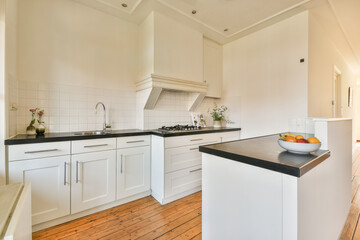 A sleek and modern kitchen with white cabinetry, minimalist design, and wooden flooring that highlights spaciousness and functionality.