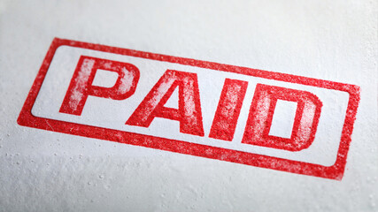 Red paid stamp impression on white textured paper