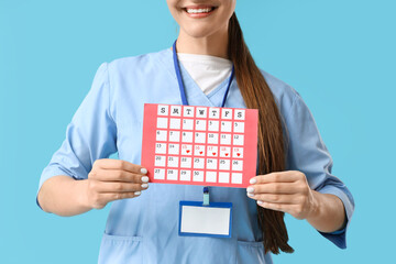 Female doctor with menstrual calendar on blue background, closeup