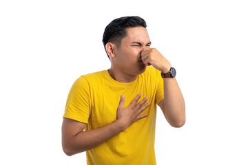 Handsome Asian man pinching his nose with fingers, smelling something smelly and disgusting...