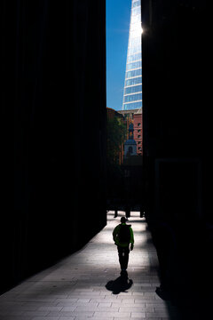 Silhouetted figure walking toward sunlight between towers, symbolizing clarity, decision and leadership in business.