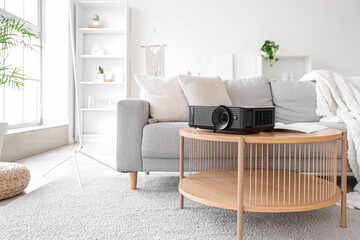 Modern projector on table in living room interior