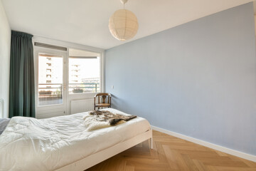 A bright and airy modern bedroom featuring a white bed, soft textures, and natural light. The calming blue wall and minimal decor create a serene atmosphere.