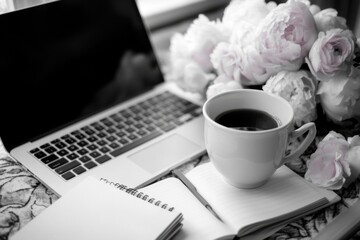 Monochrome aesthetic workspace featuring laptop, notebook, coffee cup, and soft floral arrangement, styled for feminine productivity and morning routine concepts