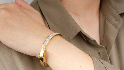 Woman wearing a gold bracelet decorated with diamonds