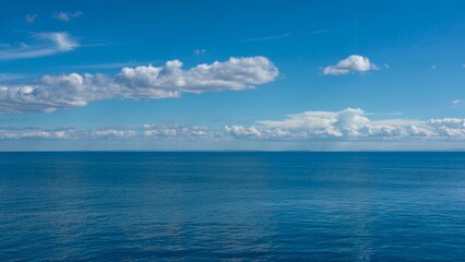 Blue sea landscape with perfectly aligned horizon with blue sky and white clouds