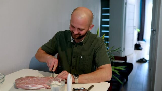 Man prepares meat in a modern kitchen during an afternoon cooking session with natural light streaming in