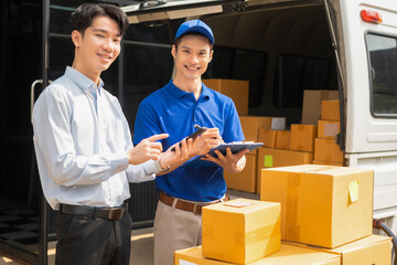 Asian man signs for parcel delivery, confirming shipment. Concept of e-commerce, logistics, and...